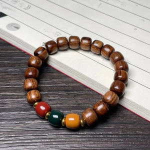Polished black rosewood bead bracelet with colorful accents on vintage calligraphy background