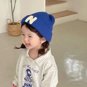 Detail of blue knit beanie with letter N patch for kids, stylish warm winter hat