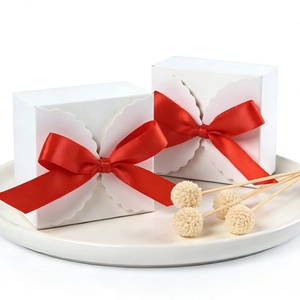 White square gift box with red satin bow and elegant wavy scalloped lace edges