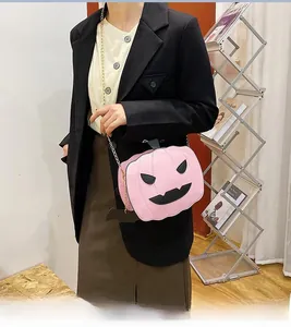 Close-up of pink pumpkin crossbody bag with black face and gold chain strap