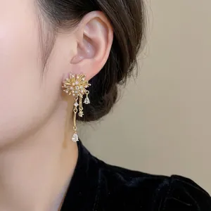 Golden tassel drop earrings with starburst zircon and pearls worn by a model
