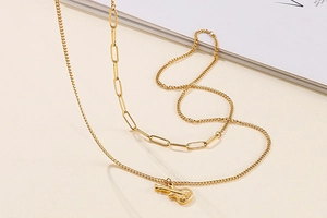 Close-up of gold double-layer necklace with guitar pendant and paperclip chain style