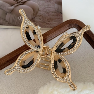 Macro view of gold alloy butterfly hair claw with rhinestones and tortoiseshell resin wings