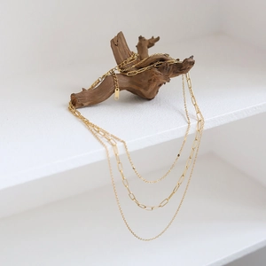 Three-layer gold stainless steel necklace with paperclip chain on natural wood