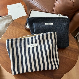 Close-up of denim and striped canvas cosmetic pouches with zipper and woven logo tags