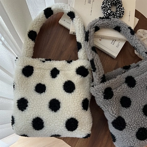 Gros plan de sacs à main en peluche à pois crème et gris sur un bureau en bois