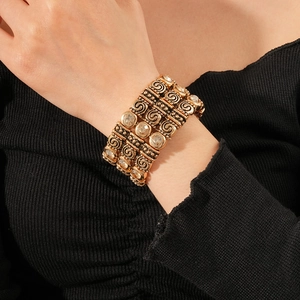 Macro detail of vintage gold multi-layer bracelet with crystal inlays and scroll patterns