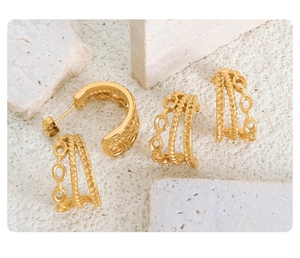 Macro detail of triple-layer C-shaped gold hoop earrings with twisted thread texture