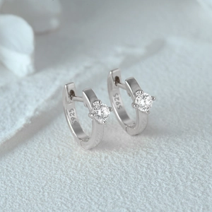 Macro shot of S925 sterling silver huggie earrings featuring a sparkling double row diamond setting