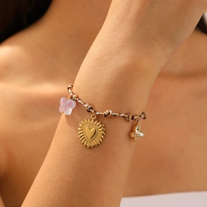 Bohemian braided rope bracelet with gold sunflower and butterfly charms on wrist
