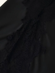 Detailaufnahme von schwarzem Satinstoff mit zarter Spitzenbordüre am Trägerkleid
