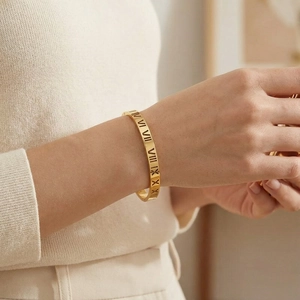 Vue détaillée d'un bracelet doré avec chiffres romains ajourés sur le poignet
