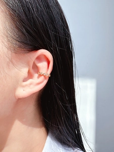 Close-up of gold ear cuff set with round clear zircons worn on the cartilage