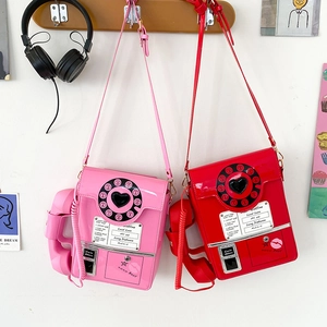 Pink and red retro phone-shaped crossbody bags hanging in a bright creative setting