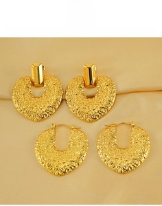 Détail macro de boucles d'oreilles cœur en acier titane doré avec texture martelée