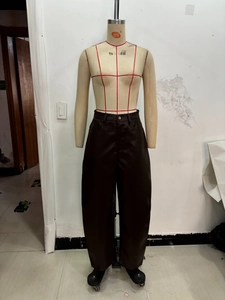 Dettaglio dei pantaloni in pelle PU marrone scuro a vita alta con bottone in metallo e tasca