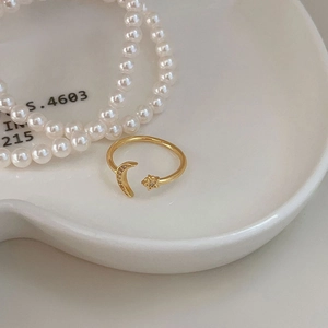 Macro detail of gold-plated crescent moon and star ring with sparkling crystal inlay