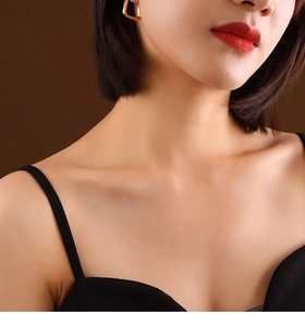 Close-up of a stylish gold U-shaped geometric earring on a model wearing black