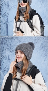 Detail of grey winter knit hat and buttoned neck warmer with faux fur pompom in snow