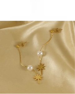 Close-up of gold tassel earrings with white pearls and eight-pointed star charms