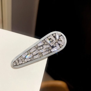 Close-up of elegant zircon arrow hair clip with sparkling crystals on white surface