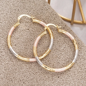 Driekleurige getextureerde oorringen in goud zilver en roségoud op stenen basis