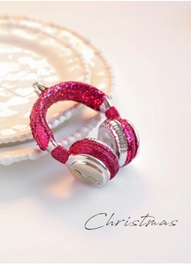 Detail of glittery pink headphone-shaped Christmas ornament with golden clef on a white plate