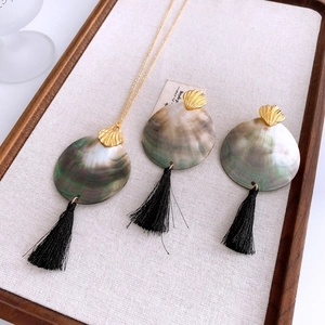 Detail view of shell necklace and tassel earrings set on light fabric display