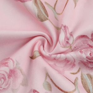 Primer plano detallado de tela de punto rosa con rosas rojas y drapeado en forma de espiral