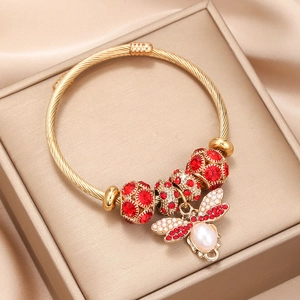 Gold twist cable bangle featuring red crystal beads and a pearl bee charm pendant