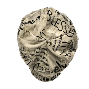 Macro shot of beige distressed beanie with black letter print and ripped hole details
