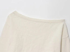 Close-up of off-white knitted sweater showing off-the-shoulder neckline and soft texture