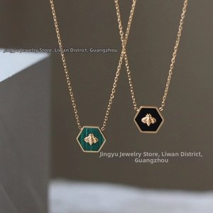 Macro view of honeycomb bee pendants with green and black enamel in 18K gold-plated titanium