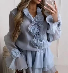 Detail of light blue chiffon top featuring 3D flowers and flared ruffle sleeves