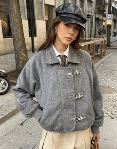 Detalle de chaqueta de lana gris con hebillas metálicas y estética de moda callejera