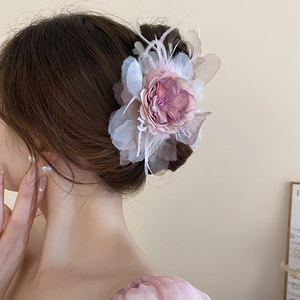 Elegant large floral hair claw with lace petals and soft feathers on a model's hair
