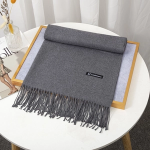 Macro detail of dark grey cashmere scarf featuring thick fabric and soft fringe tassels