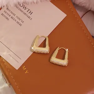 U-shaped gold-plated hoop earrings with micro-pave zircon on brown leather background