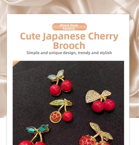 Detailed view of cherry brooches with red resin fruits and sparkling crystal leaves