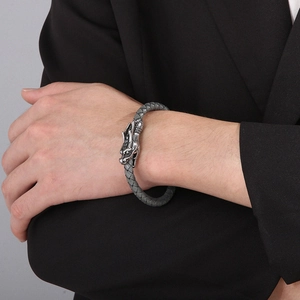 Men's braided leather dragon head bracelet with silver metallic clasp on model's wrist