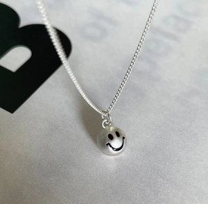 Detailed view of 925 sterling silver smiley face pendant on a thin silver chain