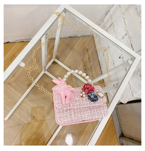 Detailed macro view of pink tweed kids handbag with pearl handle and decorative charms