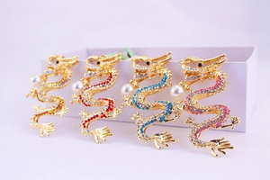 Detail of four Chinese dragon keychains in gold with colorful rhinestones and white pearls