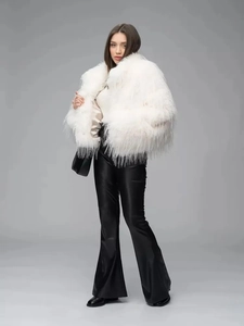 Full view of white faux fur coat paired with black glossy flare leather trousers