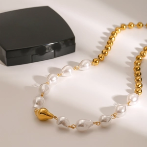 Detail of irregular white pearls and gold metal beads on a stainless steel necklace