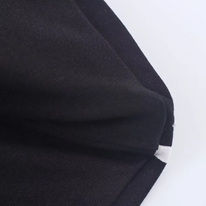 Close-up of black knitted fabric with contrast white edge stitching detail