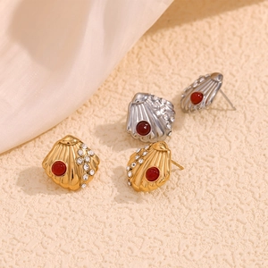 Close-up of shell-shaped earrings in gold and silver finish with red stones and crystals
