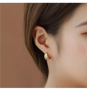 Detail of layered gold hoop earrings with multi-ring design worn by a model