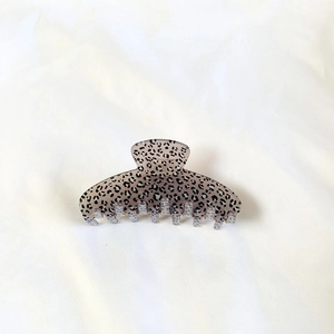 Close-up of leopard print hair claw clip on white fabric with detailed texture