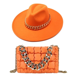 Detail von orangefarbenem Filzhut und gesteppter Handtasche mit groben Goldketten